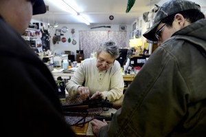 Howllowpoint Gun Shop Owner Erin Jerant helps mount a scope on a hunting rifle for Justin Noga, right, as friend Ricky Kelly looks on in Walsenburg. Jerant says she has known the two since they were young enough to sit on the store's countertops. (AAron Ontiveroz, The Denver Post)
